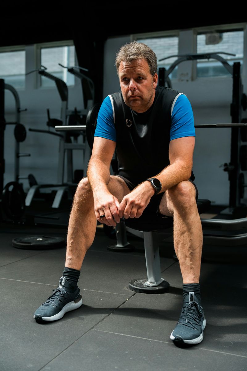 A man in his fifties resting between sets in a gym